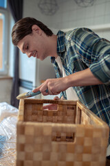 Smiling young man painting the outside of the handmade box