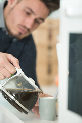 Fototapeta na wymiar man in the kitchen pouring a mug of filtered coffee