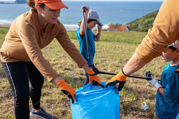Family with kids collecting garbage together on field