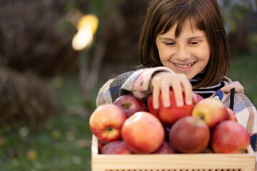 Fototapeta na wymiar Schoolkid girl's hand take red apple and eats an apple. Female hand choosing organic fruits. Portrait of healthy schoolgirl eating big red apple