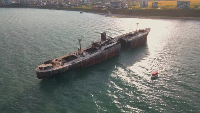Drone footage of a rusty shipwreck at the Black Sea located next to Costinesti beach, in Romania. Aerial video was shot from a drone while flying at high altitude around the shipwreck at sunset.