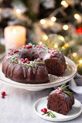 Fototapeta na wymiar Slice of Christmas chocolate bundt cake decorated cranberries and rosemary