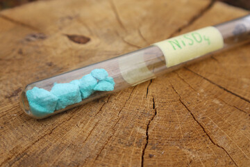 Pieces of toxic blue nickel sulfate in a test tube, a substance used as an ingredient in a fungicide mixture and to make battery electrolytes.