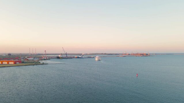 Aerial view of a harbor with ships sailing and docked. Footage was taken from a drone at a higher altitude in summer season at sunset in Navodari harbour, Romania.