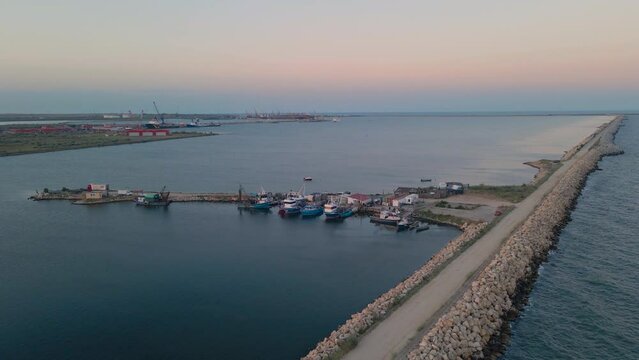Aerial view of a harbor with fishing boats docked. Footage was taken from a drone at a higher altitude in summer season at sunset in Navodari harbor, Romania.