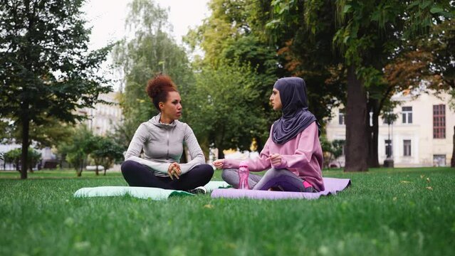 Multiethnic female friends talking and working out outdoors, training partners