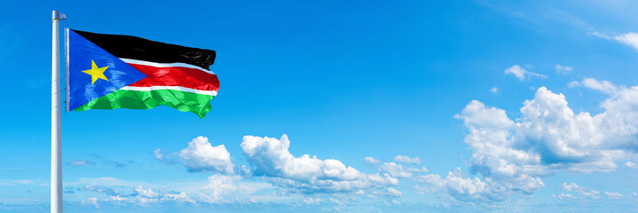 South Sudan flag waving on a blue sky in beautiful clouds - Horizontal banner