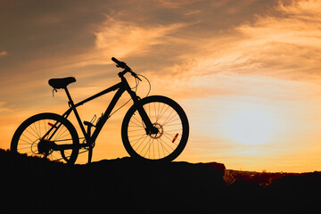 Fototapeta na wymiar silhouette of a bicycle on a hill, wheels in the grass and sunlight