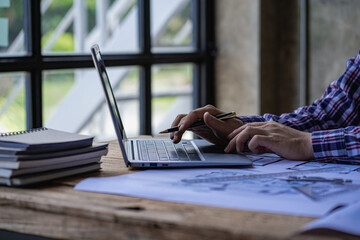 A close-up view of engineers drawing plans and measurements at work. Architects design, work, draw, sketch, and model architectural construction in the home.
