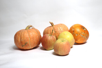 a pile of apples and pumpkins against light background