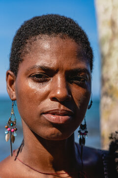 Retrato en primer plano de una mujer africana con cabello corto afro viendo a c&aacute;mara en un d&iacute;a soleado en una playa del caribe en Costa Rica 