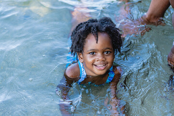 Retrato horizontal de una pequeña niña afroamericana de cabello afro muy sonriente y mirando a...