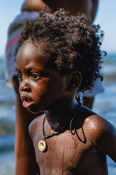 Retrato vertical del perfil de un peque&ntilde;o ni&ntilde;o afroamericano de cabello afro mojado en la playa en un d&iacute;a de verano. 