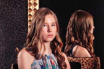 Obraz na płótnie Canvas Portrait of pretty cute teenager girl in an elegant dress at mirror