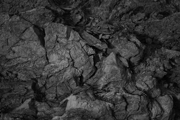 Black white rock texture. Close-up. Dark gray stone background for design. Crumbled, broken, ruined.