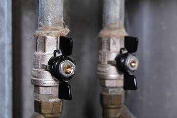 Black brass ball shut-off valves on water supply pipeline in the house, plumbing and construction concept