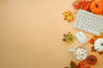 Fall office workspace. Keyboard, laptop, mug with autumn cloth and fall decorations - pumpkin, leaves and other.