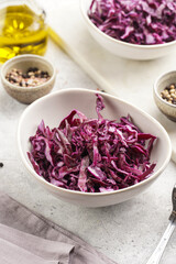 Two salad bowls with german red cabbage chopped in fine stripes on marble board on grey background