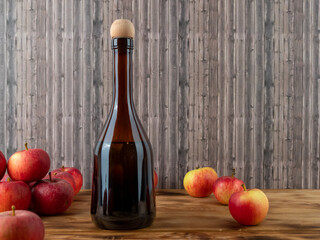 Apple cider vinegar in a bottle with apples on a wooden background.