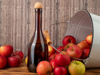 Apple cider vinegar in a bottle with apples on a wooden background.