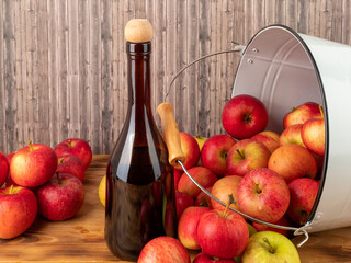Apple cider vinegar in a bottle with apples on a wooden background.