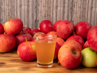 Apple cider vinegar in a glass with apples on a wooden background.