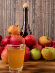 Apple cider vinegar in a glass with apples on a wooden background.