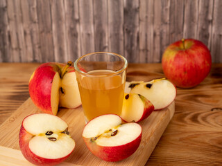 Apple cider vinegar in a glass with apples on a wooden background.