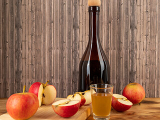 Apple cider vinegar in a bottle with apples on a wooden background.