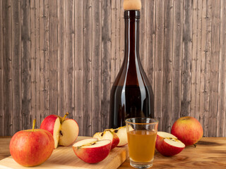 Apple cider vinegar in a bottle with apples on a wooden background.