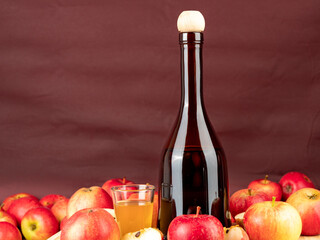 Apple cider vinegar in a bottle with apples on a brown background.