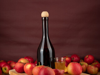 Apple cider vinegar in a bottle with apples on a brown background.