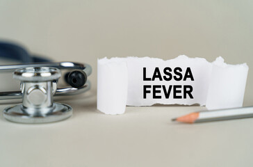On a gray background, a stethoscope, a pencil and a paper plate with the inscription - Lassa fever