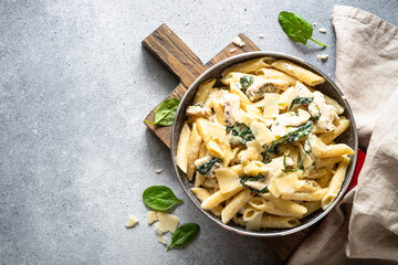 Pasta penne with chicken and spinach in creamy sauce, top view.