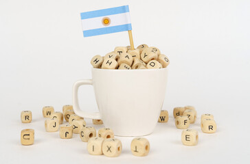 The flag of Argentina sticks out of a cup with dice on which letters are depicted