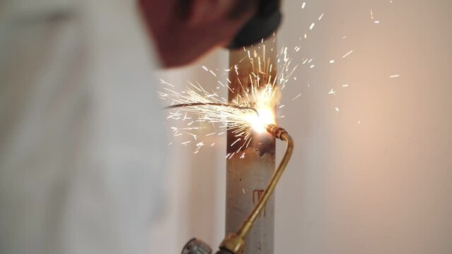 worker soldering the pipe by gas welding