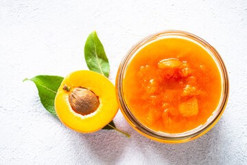 Apricot jam in glass jar, homemade preservation at white. Top view with copy space.