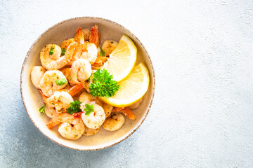 Frying shrimps with lemon and herbs in the craft bawl. Top view image on light background.
