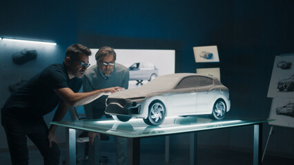 Experienced automotive designers and car developers discuss the design infront of a rake sculpt...