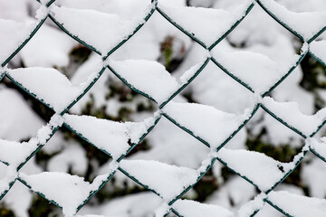 Chain link fence with snow background in wintertime