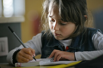 Naklejka premium Young girl 6-7 years old drawing