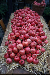 Harvest of ripe pomegranate on dry straw at outdoor farmers market in Tbilisi Georgia. Vegetarian healthy food