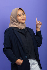 Asian Muslim Woman Pointing at Copy Space on Purple Background