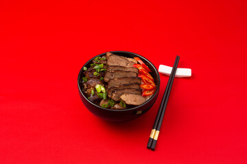 Bowl of rice, beef and vegetables on red background