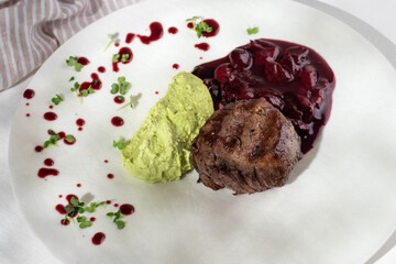 Restaurant Food - Filet mignon with edamame puree and cherry demiglace sauce on a white plate.