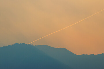 Airplane vapor trail in smokey sky