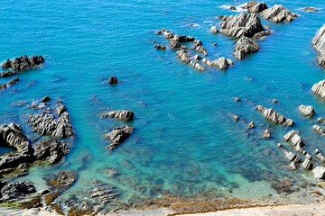 Scattered sharp rocks in the azure blue and turquoise sea
