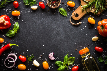 Food frame. Food cooking background on black stone table. Fresh vegetables, herbs and spices. Top...