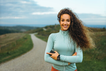 A girl is smiling with a smart phone in her hand, listening to music, and showing her smart watch.