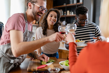 Young diverse people having a holiday party at home, preparing food, drinking, talking, and enjoying